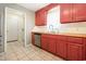 Kitchen featuring red cabinetry, a stainless steel dishwasher, and tiled flooring at 706 Chippendale Dr., Myrtle Beach, SC 29588