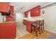 Cozy kitchen featuring red cabinets, a breakfast bar with cushioned stools, and tiled flooring at 706 Chippendale Dr., Myrtle Beach, SC 29588