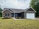 New construction home features a stone facade, dark siding, manicured landscaping, and attached two car garage at 718 Highway 348, Loris, SC 29569