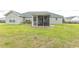 Backyard view showcasing the rear of the house, a screened porch, and expansive green lawn at 908 Hornbeam Ct., Loris, SC 29569