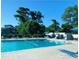 Spacious community pool surrounded by lush trees, sun loungers, and tables under blue umbrellas at 913 Villa Dr. # 913, North Myrtle Beach, SC 29582
