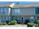 Inviting townhouse exterior with light gray facade and blue shutters, showcasing well-maintained landscaping at 913 Villa Dr. # 913, North Myrtle Beach, SC 29582