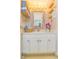 Bright bathroom with large framed mirror, gold storage shelves, marble countertops, and white cabinets with gold pulls at 200 76Th Ave. N # 408, Myrtle Beach, SC 29572