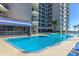 Sparkling blue pool with chairs and palm trees, next to condo building, offering a relaxing waterfront retreat at 200 76Th Ave. N # 408, Myrtle Beach, SC 29572
