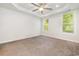 Spacious bedroom featuring a tray ceiling, neutral carpet, two large windows, and a ceiling fan with light at 2409 Thoroughfare Dr. # 2409, North Myrtle Beach, SC 29582
