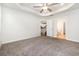 Large bedroom featuring tray ceilings, neutral carpet, a ceiling fan, and an ensuite bathroom and closet at 2409 Thoroughfare Dr. # 2409, North Myrtle Beach, SC 29582