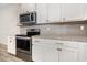 Close up of kitchen featuring stainless oven, microwave, white cabinets, granite counters, and gray subway tile backsplash at 2409 Thoroughfare Dr. # 2409, North Myrtle Beach, SC 29582
