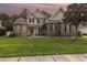 Beautiful two-story brick home with manicured lawn, professional landscaping, complemented by colorful sunset sky above at 3564 Brampton Dr., Myrtle Beach, SC 29588