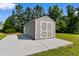 A gray storage shed with white trim, double doors and a concrete pad sits against a backdrop of tall trees at 3926 Long Avenue Ext., Conway, SC 29527