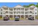 Three-story condo building with white balconies, green shutters, and well-maintained landscaping at 4429 Turtle Ln. # 3A, Little River, SC 29566