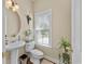 Charming half-bath showcases a pedestal sink, decorative mirror, and bright window with natural light at 5916 Falcon Landing Circle, North Myrtle Beach, SC 29582
