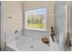 Bright bathroom with a large soaking tub under a window overlooking the lawn at 5916 Falcon Landing Circle, North Myrtle Beach, SC 29582