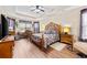 Main bedroom with wood floors, ceiling fan, tray ceilings, desk, and a luxurious decorative wooden bed frame at 5916 Falcon Landing Circle, North Myrtle Beach, SC 29582