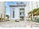 Exterior of a beachfront building featuring balconies, covered parking, and nearby palm trees at 6172 Catalina Dr. # 214, North Myrtle Beach, SC 29582