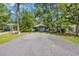 View of the house surrounded by mature trees and lawn, accessible by a paved driveway at 6612 Wintergreen Point, Myrtle Beach, SC 29588