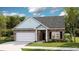 Charming single-Gathering home featuring stone accents, light blue shingle details and an attached two-car garage at 8719 Baton Rouge Ave Nw, Calabash, NC 28467