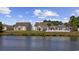 Back view of residences from across a tranquil lake, set against a backdrop of a beautiful, partly cloudy sky at 886 Carolina Farms Blvd., Myrtle Beach, SC 29579