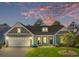 Charming home with a two-car garage, a well-manicured lawn and cozy front porch under a colorful sky at 9169 Nw Oldfield Rd., Calabash, NC 28467