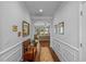 Long hallway featuring hardwood floors and classic wainscoting, leading to a naturally lit living space at 9169 Nw Oldfield Rd., Calabash, NC 28467