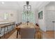 Bright dining room with a long wooden table, seating for eight, modern lighting, and views of the outdoors at 93 Knotty Pine Way, Murrells Inlet, SC 29576