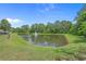 Scenic pond with a fountain, surrounded by green grass and mature trees at 100 Oak Leaf Dr., Longs, SC 29568
