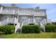 Close up of the exterior townhouse complex with white stairs and greenery at 112 3Rd Ave. S # B, Surfside Beach, SC 29575