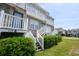 Townhouse exterior with white stairs and green shrubbery against a blue sky at 112 3Rd Ave. S # B, Surfside Beach, SC 29575