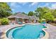 Gorgeous backyard pool with a tanning ledge, patio, and a brick home with lush landscaping at 1203 Crooked Oak Dr., Pawleys Island, SC 29585