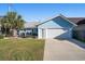 Charming blue house featuring an attached garage, green lawn, and palm tree at 1415 Edge Dr., North Myrtle Beach, SC 29582