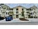 Inviting exterior view of a charming two-story condo building with palm trees and well-maintained landscaping at 144 Puffin Dr. # 1-A, Pawleys Island, SC 29585