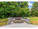 Backyard with stone patio featuring a cozy stone fire pit surrounded by lush landscaping at 1720 Horry St., Conway, SC 29526