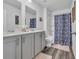 Bright bathroom featuring a double vanity, decorative mirror, and bathtub with a floral shower curtain at 1748 Promise Pl., Myrtle Beach, SC 29588