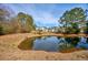 Scenic view of a pond reflecting the sky and nearby houses, surrounded by natural landscaping at 229 Duchess Ct., Myrtle Beach, SC 29588
