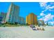 Picture of condo buildings behind a sandy beach with groups of people sitting in chairs under a sunny blue sky at 2404 N Ocean Blvd. # 635, Myrtle Beach, SC 29577