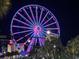 View of the SkyWheel, a vibrant Ferris wheel illuminated at night, surrounded by palm trees and city lights at 2404 N Ocean Blvd. # 635, Myrtle Beach, SC 29577