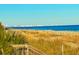 Scenic ocean view with golden beach and distant skyline, captured from a wooden deck with lush vegetation at 2404 N Ocean Blvd. # 635, Myrtle Beach, SC 29577