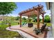 Backyard patio with a wooden pergola, cushioned seating, and view of the lush landscaping and pond at 274 Avenue Of The Palms, Myrtle Beach, SC 29579