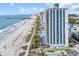 High-rise condo on a sandy beach with many colorful umbrellas, a beautiful ocean view, and inviting pools at 3000 N Ocean Blvd. # 220, Myrtle Beach, SC 29577