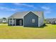 Rear view of a house with a covered patio, blue siding, white trim, and a well-maintained lawn at 383 Hayloft Circle, Conway, SC 29526