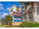 The Dunes Village Resort sign features vibrant colors, nearby palm trees, and tropical landscaping at 5300 N Ocean Blvd. # 422, Myrtle Beach, SC 29572