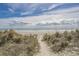 Inviting sandy path leading to a beautiful beach with gentle waves and a serene sky, perfect for relaxation at 5751 Oyster Catcher Dr. # 334, North Myrtle Beach, SC 29582