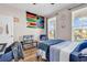 Comfortable bedroom with a blue bedspread, mounted TV, and flags above the bed at 684 Wailea Circle, Little River, SC 29566