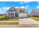 Charming blue home with a two-car garage, landscaped yard, and inviting front porch on a sunny day at 684 Wailea Circle, Little River, SC 29566