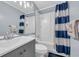 Bright bathroom features a vanity and a shower-tub combo with a blue and white shower curtain at 9400 Shore Dr. # 206, Myrtle Beach, SC 29572