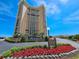 Stunning exterior view of the condo building with colorful landscaping and signage against a bright, blue sky at 9650 Shore Dr. # 1203, Myrtle Beach, SC 29572