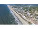 Aerial view of a coastal community showcasing the sandy beach, ocean waves, residential buildings, and neighborhood streets at 1011 S Ocean Blvd., Surfside Beach, SC 29575