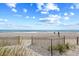 Beautiful sandy beach scene, framed by dune grasses and a wooden fence, inviting relaxation at 107 S Ocean Blvd. # 1402, Myrtle Beach, SC 29577