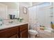 Well-lit bathroom with a white shower curtain, dark wood cabinets, and floral decorations at 1434 Chanson Ct., Little River, SC 29566