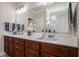 Bathroom featuring double sinks, white countertops, and dark wood cabinets and a large mirror at 1434 Chanson Ct., Little River, SC 29566