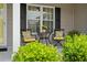 Cozy front porch seating area with black metal chairs and potted plants by shuttered windows at 1536 Abberbury Dr., Conway, SC 29527